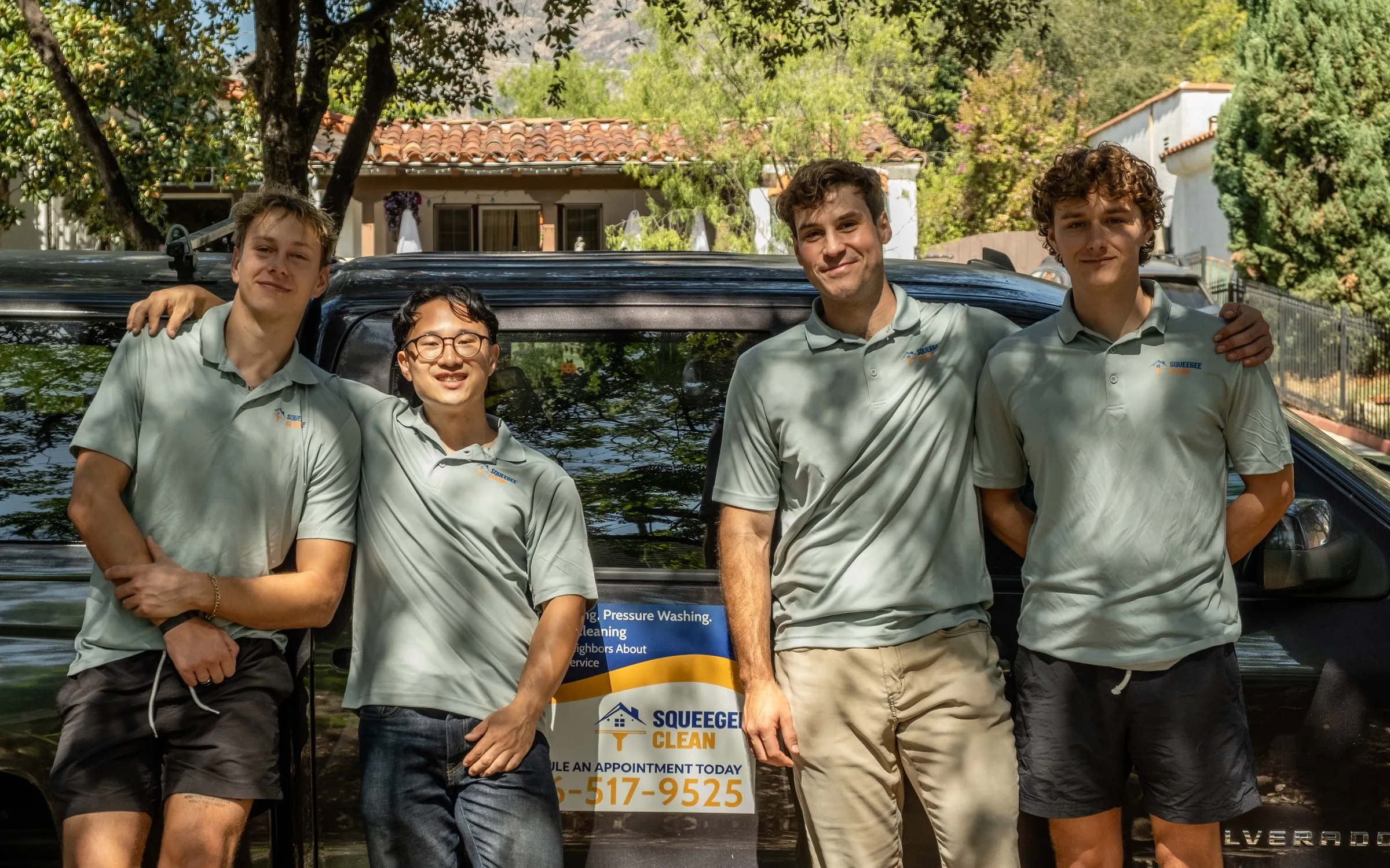 Jordan, Wes, Elliott, and Jonathan of Squeegee Clean Windows in uniform polos beside the company truck